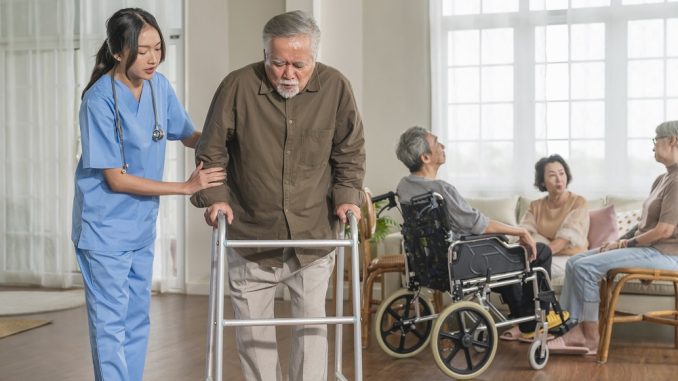 young-asian-female-nurse-care-giver-helping-asian-senior-old-man-with-mobility-walker-living-area-nursing-home-senior-daycare-centernurse-take-care-elderly-patient-with-cheerful-concentrate